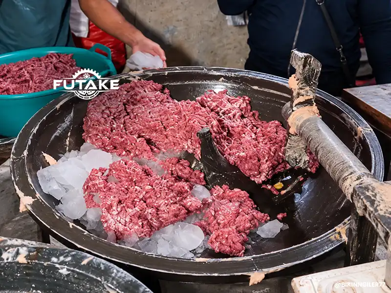 mesin giling daging bakso yang sedang menggiling daging dan ada es batunya