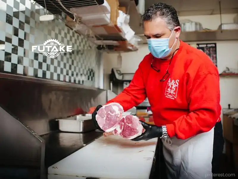 orang yang sedang memotong daging untuk digiling menggunakan mesin giling daging